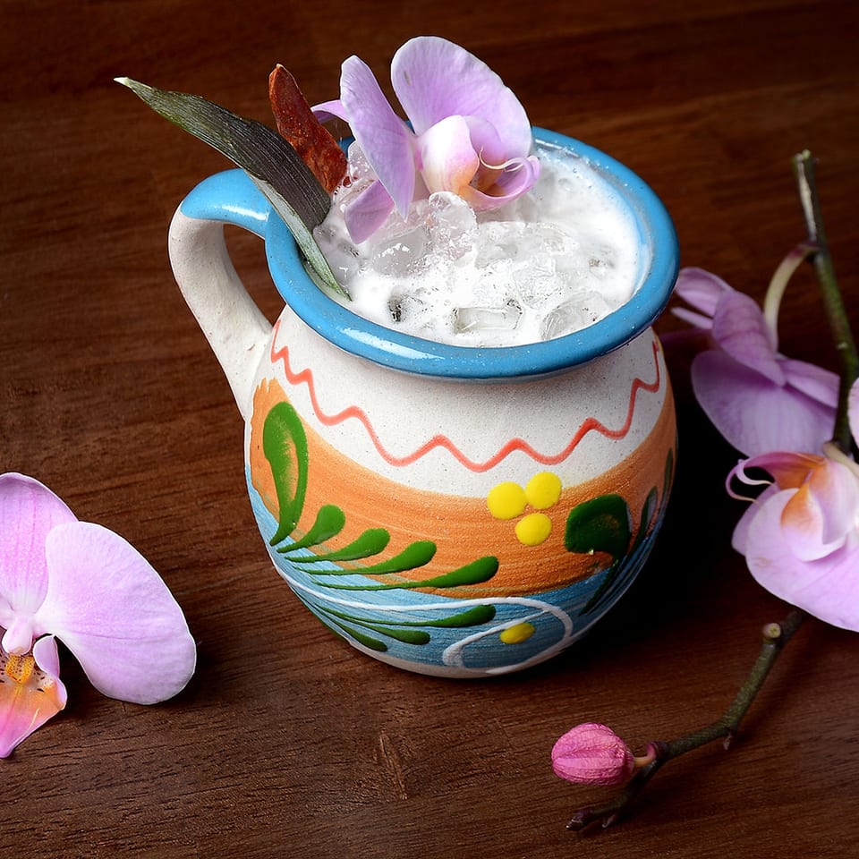 Cocktail in a ceramic mug with orchid garnish