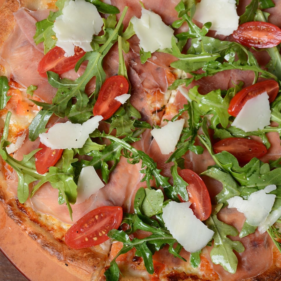 Pizza with prosciutto arugula and tomatoes